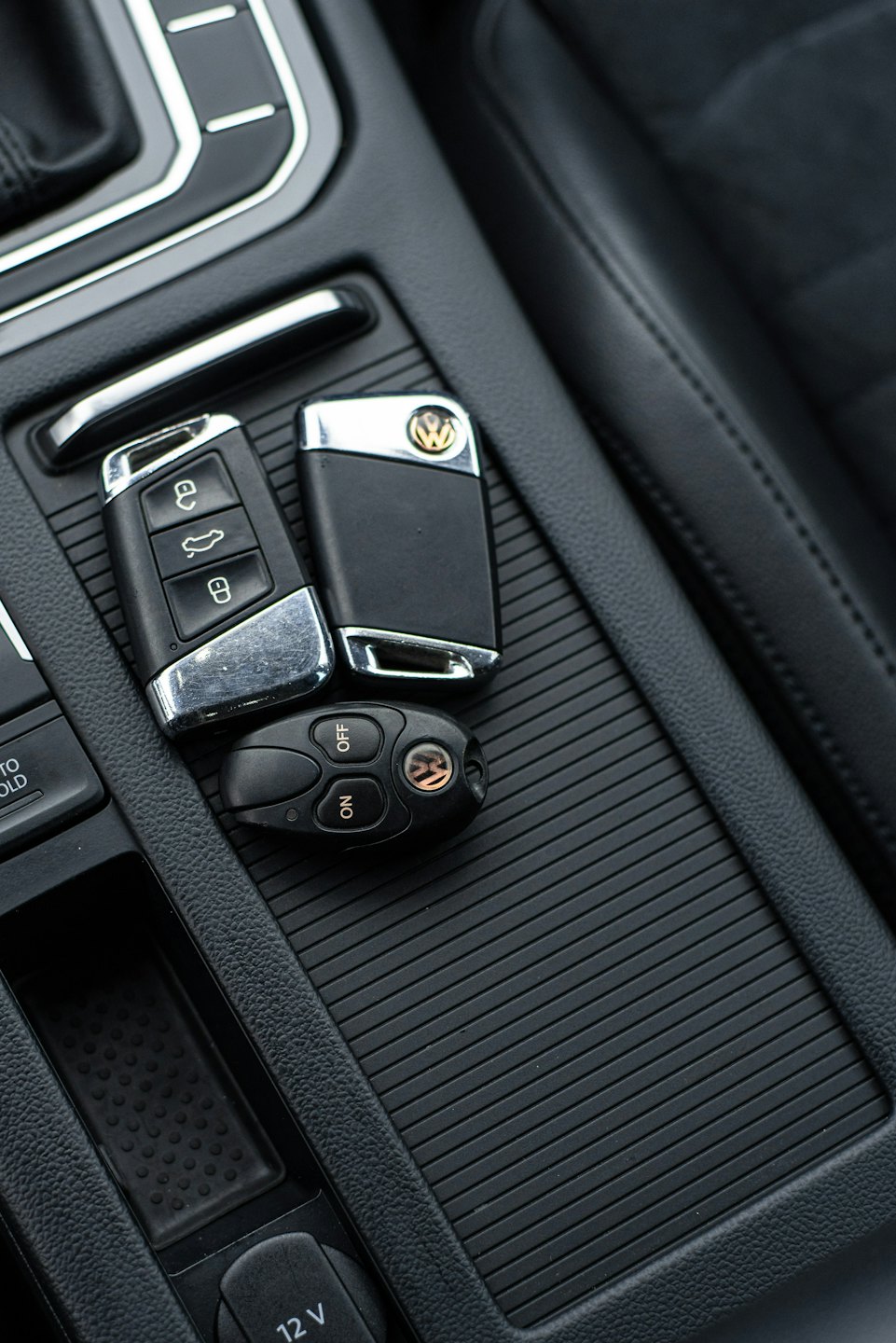 Three car key fobs resting on a vehicle center console.