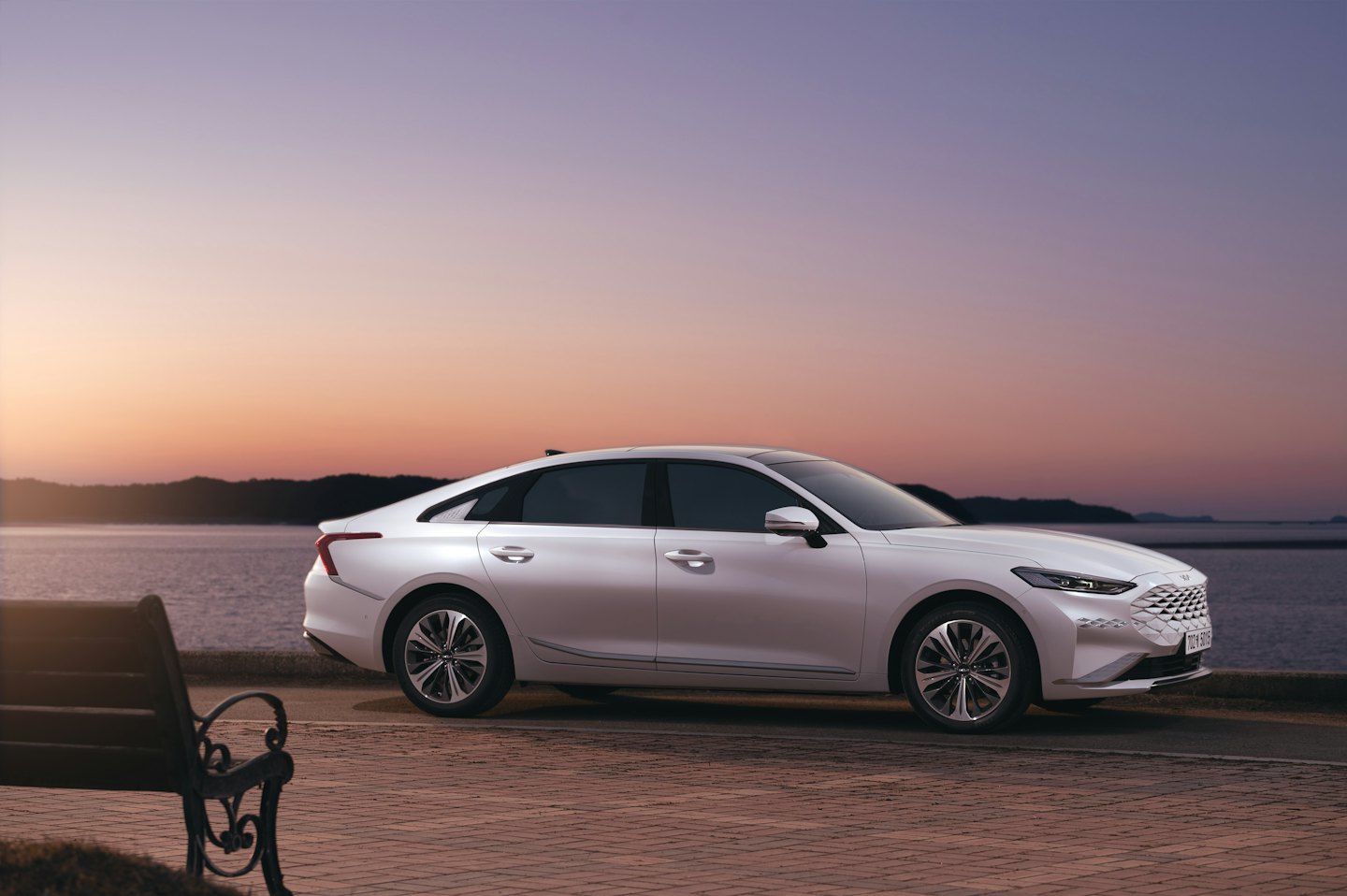 A white sedan parked on a brick waterfront road.